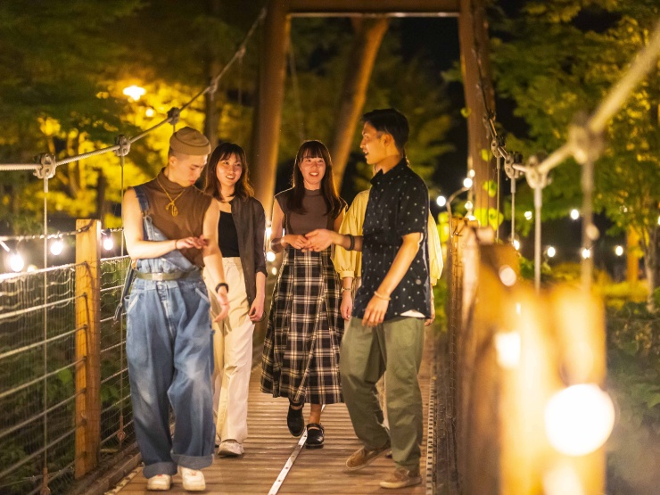関東・栃木県にあるグランピング施設ザランタン鹿沼で橋を渡りながら友人グループが談笑している様子