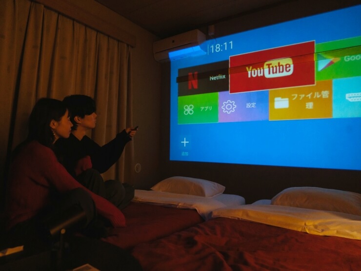 和室でプロジェクターを楽しみながらレイトチェックアウトでゆっくりと過ごすカップル