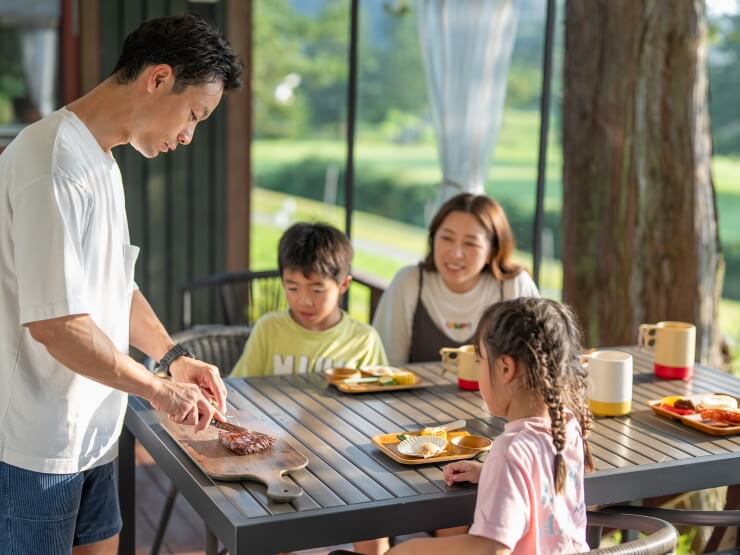 屋外デッキで家族でBBQをしている様子